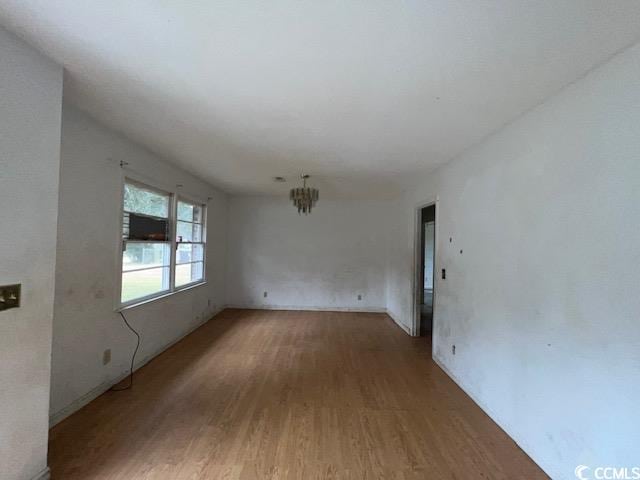 unfurnished room featuring hardwood / wood-style flooring and an inviting chandelier