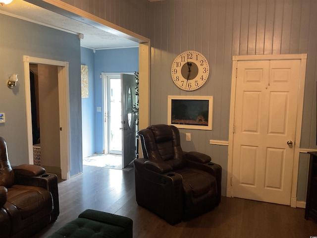 sitting room with wood walls, dark hardwood / wood-style flooring, and ornamental molding