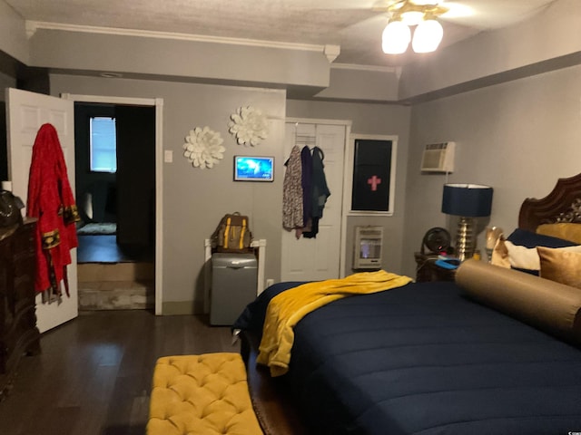 bedroom with crown molding, hardwood / wood-style flooring, ceiling fan, a wall unit AC, and a closet