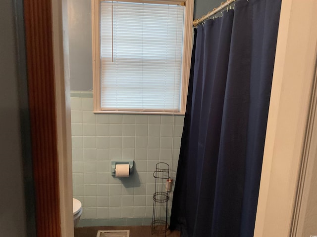 bathroom with toilet and tile walls