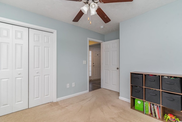 recreation room featuring ceiling fan, light colored carpet, and a textured ceiling