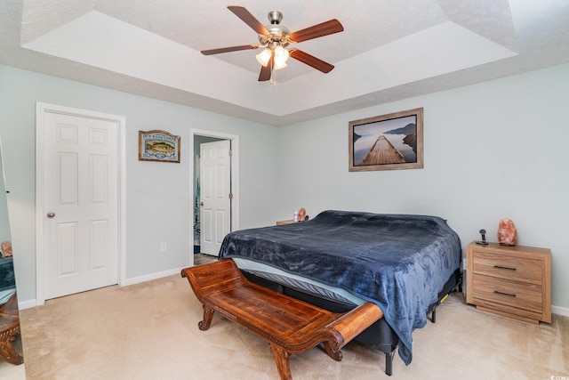 carpeted bedroom with a tray ceiling, ceiling fan, and a textured ceiling