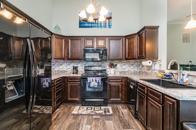 kitchen with sink, dark hardwood / wood-style flooring, a chandelier, decorative light fixtures, and black appliances