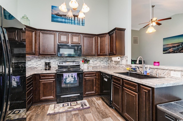 kitchen with hardwood / wood-style floors, sink, hanging light fixtures, and black appliances