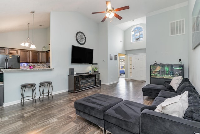 living room featuring ceiling fan with notable chandelier, dark hardwood / wood-style floors, and high vaulted ceiling