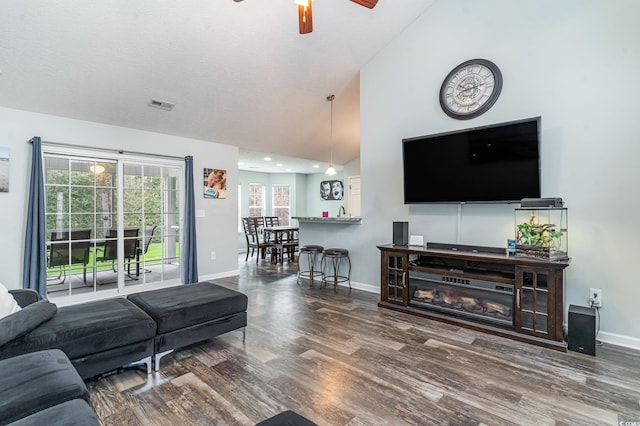 living room featuring a textured ceiling, ceiling fan, dark hardwood / wood-style flooring, and vaulted ceiling