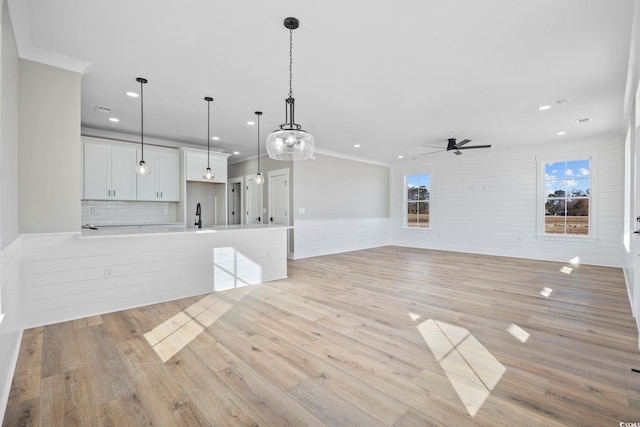 unfurnished living room with sink, ornamental molding, ceiling fan, and light hardwood / wood-style flooring