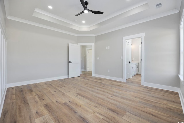 unfurnished bedroom featuring light hardwood / wood-style floors, ceiling fan, ornamental molding, a tray ceiling, and ensuite bathroom