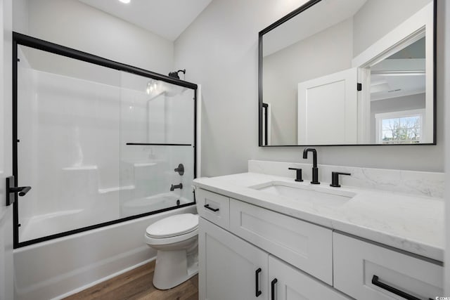 full bathroom featuring toilet, enclosed tub / shower combo, vanity, and hardwood / wood-style floors