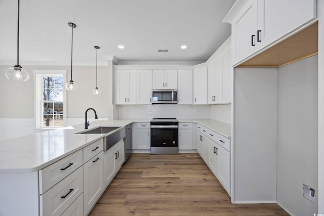 kitchen featuring appliances with stainless steel finishes, hanging light fixtures, white cabinets, and kitchen peninsula