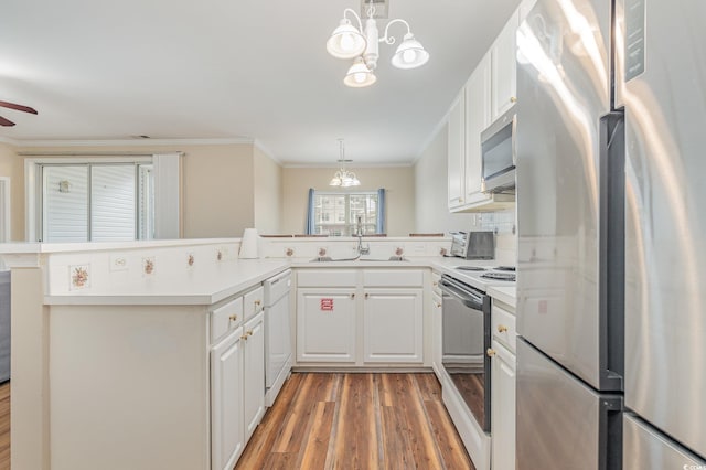 kitchen featuring sink, white cabinetry, decorative light fixtures, appliances with stainless steel finishes, and kitchen peninsula