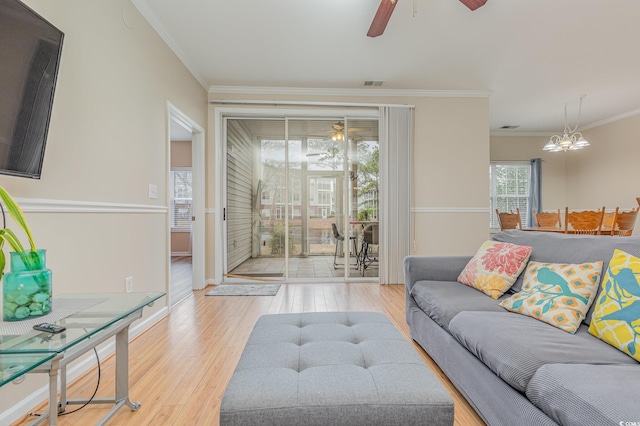 living room featuring wood-type flooring, ceiling fan with notable chandelier, and crown molding