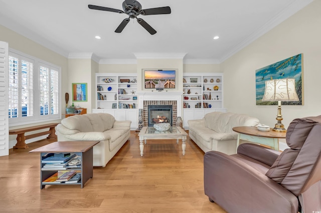 living room featuring a brick fireplace, ornamental molding, ceiling fan, built in features, and light hardwood / wood-style flooring