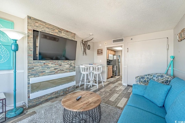 2311 S Ocean Blvd Unit 1125, Myrtle Beach, SC 29577 - living room with a textured ceiling, baseboards, visible vents, wood finished floors, and a stone fireplace