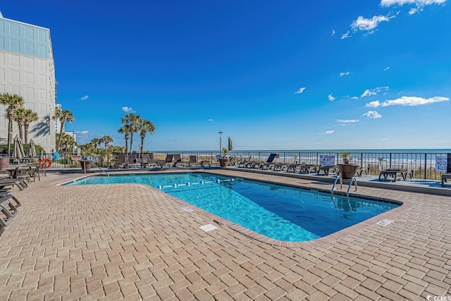 view of swimming pool featuring a water view and a patio