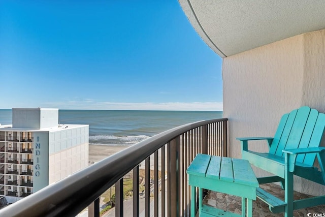 balcony with a water view and a view of the beach