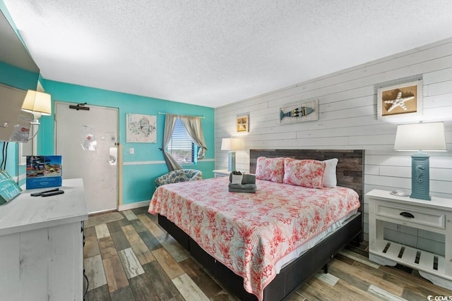 bedroom featuring a textured ceiling, wood walls, and dark wood-type flooring