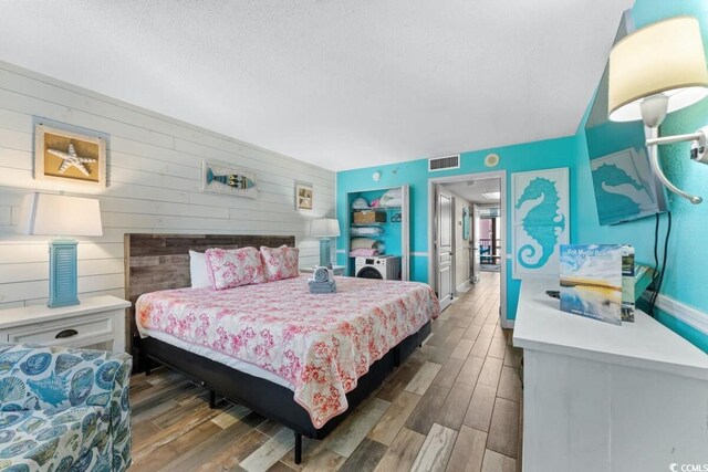 2311 S Ocean Blvd Unit 1125, Myrtle Beach, SC 29577 - bedroom with wooden walls, wood finished floors, visible vents, baseboards, and a textured ceiling