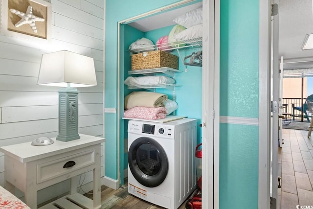 clothes washing area featuring wooden walls, dark wood-type flooring, and washer / dryer