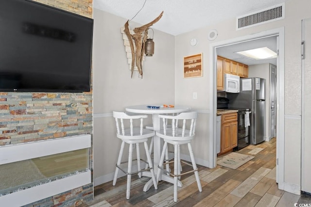 kitchen featuring a textured ceiling, black electric range oven, and stainless steel refrigerator