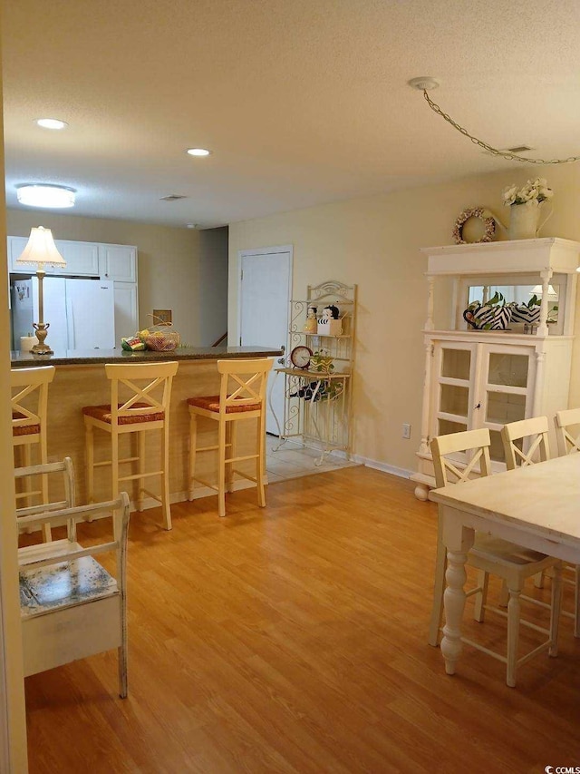 dining area featuring wood-type flooring and indoor bar