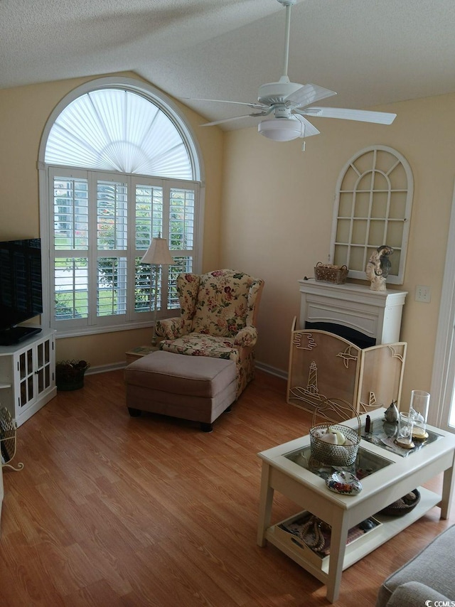 living room with hardwood / wood-style floors, a textured ceiling, ceiling fan, and lofted ceiling