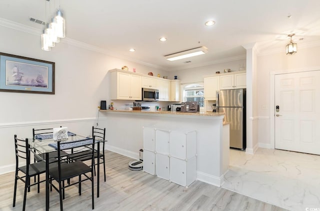 kitchen featuring appliances with stainless steel finishes, decorative light fixtures, white cabinets, ornamental molding, and kitchen peninsula