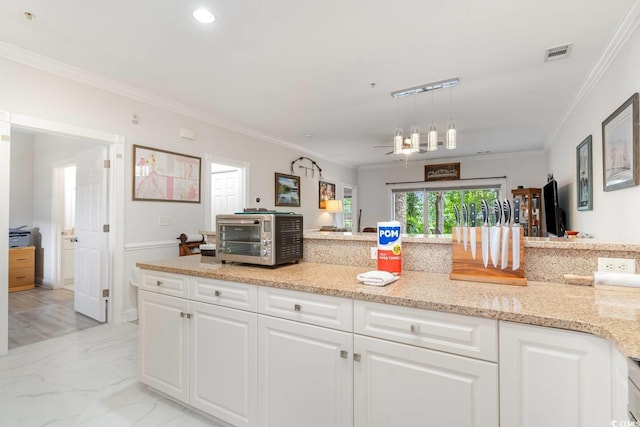 kitchen with white cabinetry, light stone counters, crown molding, and decorative light fixtures