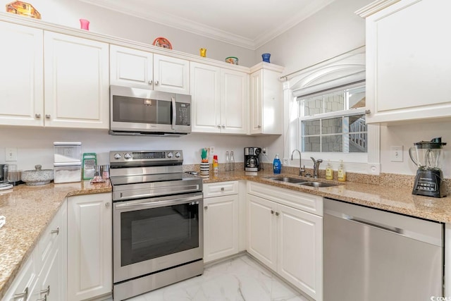 kitchen with appliances with stainless steel finishes, white cabinetry, sink, light stone counters, and crown molding