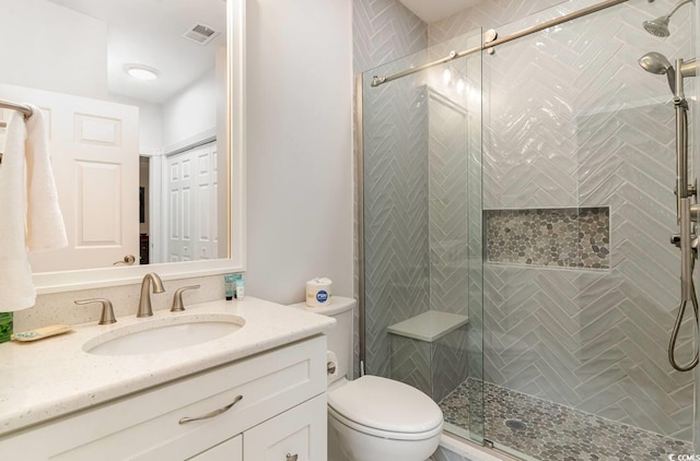 bathroom with vanity, toilet, and a shower with door