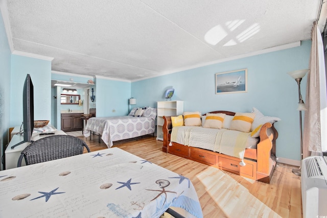 bedroom featuring a textured ceiling, hardwood / wood-style flooring, and ornamental molding