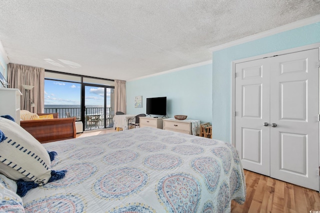 bedroom with access to exterior, crown molding, a wall of windows, light hardwood / wood-style floors, and a closet