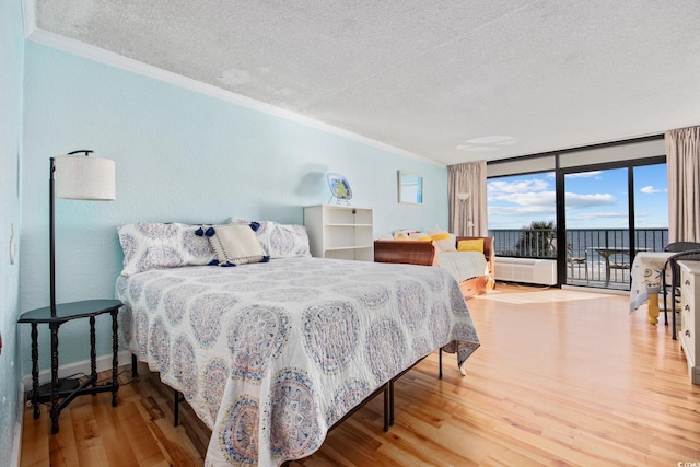 bedroom with access to outside, crown molding, hardwood / wood-style flooring, a wall of windows, and radiator heating unit