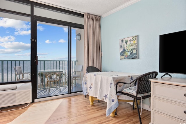 bedroom featuring access to exterior, light hardwood / wood-style floors, a water view, and a wall of windows