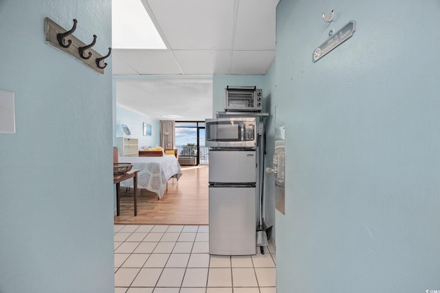 kitchen featuring light tile patterned floors, stainless steel appliances, and a drop ceiling