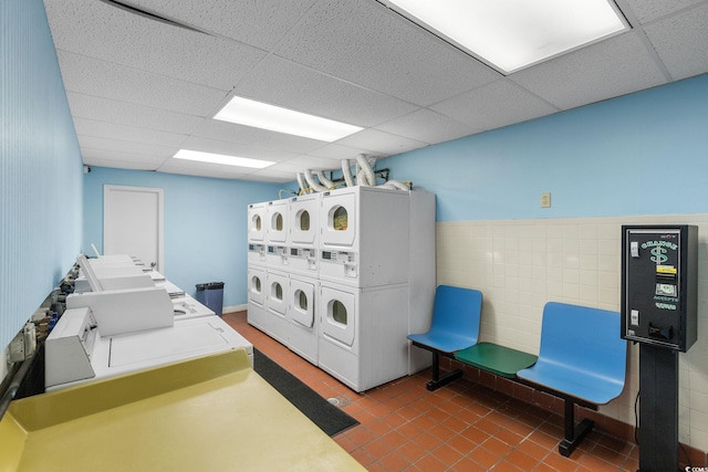 clothes washing area with washer and dryer, dark tile patterned floors, and stacked washer and clothes dryer