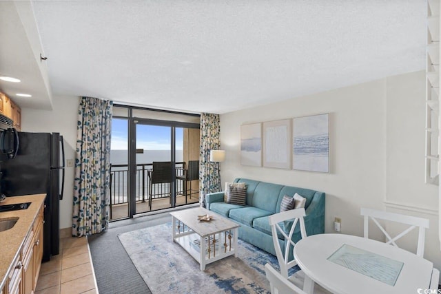 tiled living room with a textured ceiling, a water view, and expansive windows