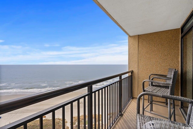 balcony with a water view and a view of the beach