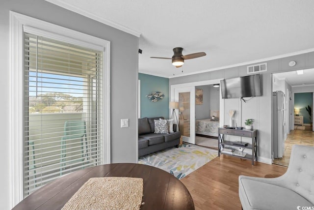 living room featuring ceiling fan, hardwood / wood-style floors, and ornamental molding