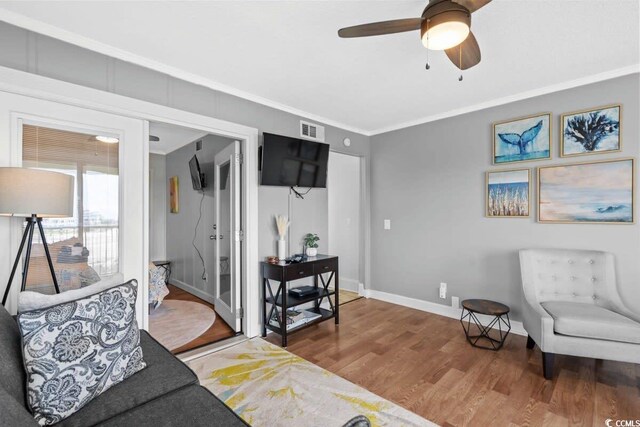 living area with crown molding, ceiling fan, and wood-type flooring