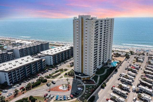 aerial view at dusk with a water view and a view of the beach