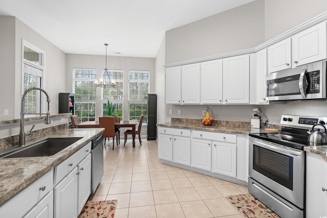 kitchen featuring appliances with stainless steel finishes, white cabinetry, a notable chandelier, and sink