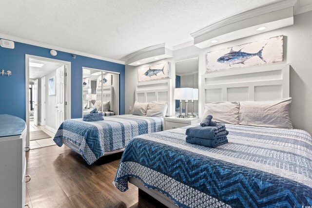 bedroom with a textured ceiling, dark wood-type flooring, and ornamental molding