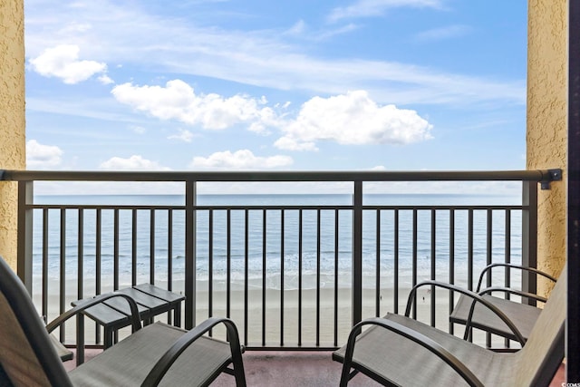 balcony with a water view and a view of the beach