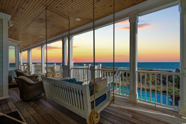 deck at dusk featuring a water view