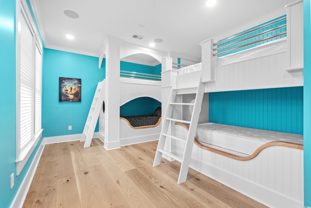 bedroom featuring light hardwood / wood-style floors, crown molding, and multiple windows