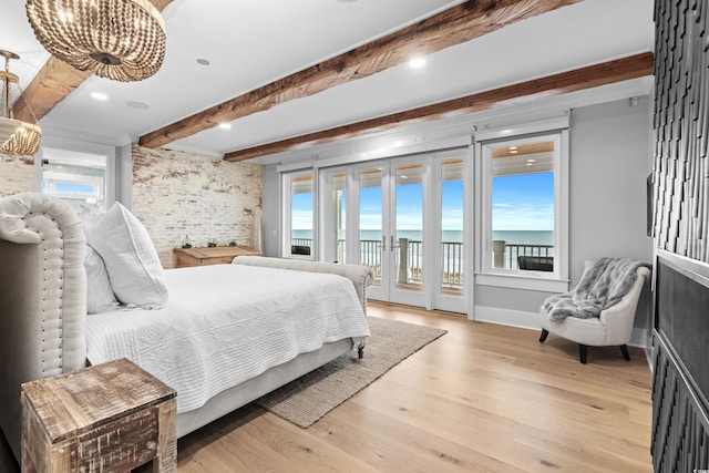 bedroom with a water view, light hardwood / wood-style flooring, access to exterior, beam ceiling, and brick wall