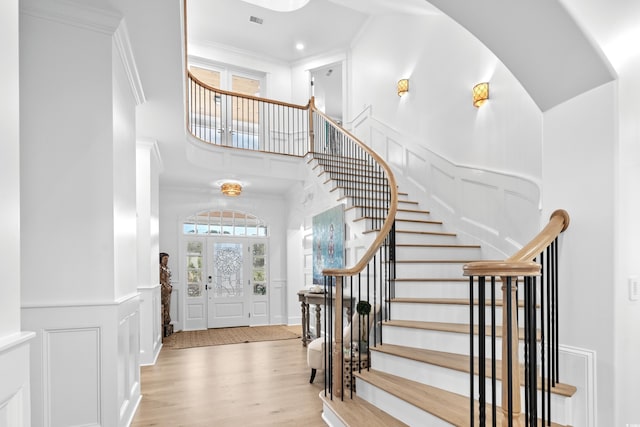 entrance foyer with a towering ceiling, light hardwood / wood-style flooring, and crown molding