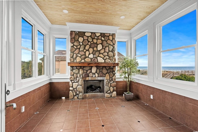 unfurnished sunroom with a water view, wooden ceiling, and a fireplace