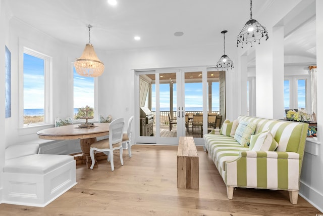 interior space featuring a healthy amount of sunlight, a water view, light hardwood / wood-style flooring, and an inviting chandelier